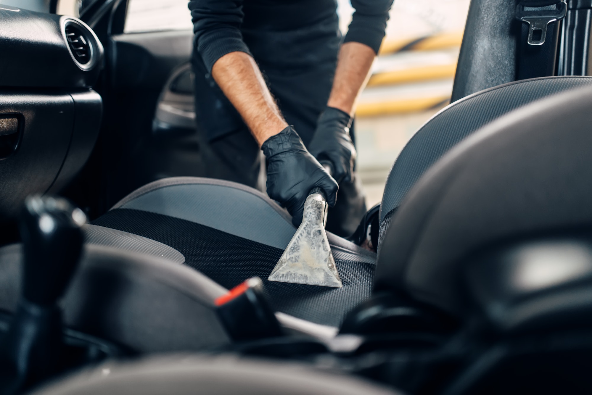a person cleaning the seat of a car